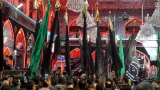 عبور دادن پرچم ها از میان زوار در حرم امام حسین علیه السلام