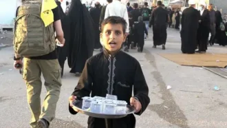 پذیرایی پسر بچه از زوار با آب خنک