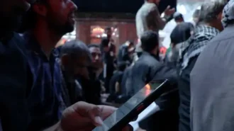مردی که از روی گوشی در حال خواندن زیارتنامه است