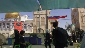 جوانی که در گوشه ای از مسیر پیاده روی، پرچم روسیه را در دست می چرخاند